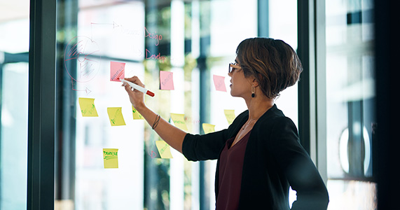 woman writing on post-it notes to outline effective channel partner strategy