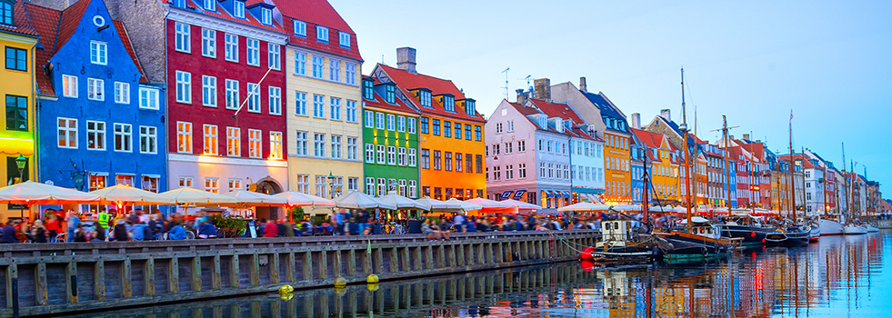 people walking and sitting at cafes along canal in Copenhagen, Denmark