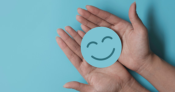 hands holding cutout of smiley face to represent customer appreciation