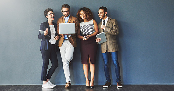 group of happy employees gathered around a laptop