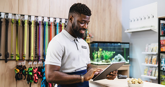 retail pet store worker using employee engagement platform on tablet