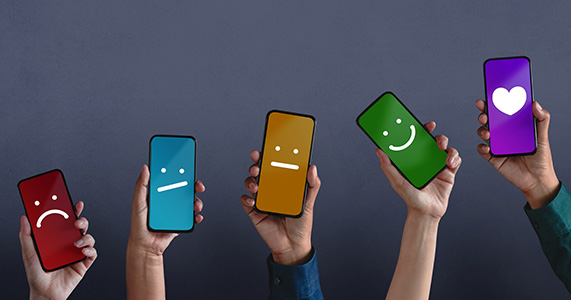 hands holding phones with emoji expressions onscreen