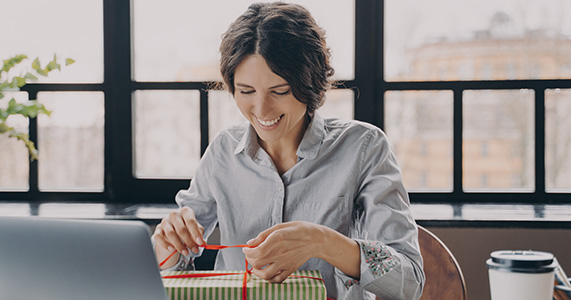 happy employee opening holiday gift from employer