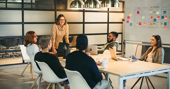 leader addresses team of employees meeting in boardroom